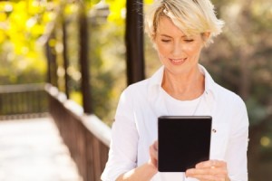 21513014 - beautiful senior woman using tablet computer outdoors